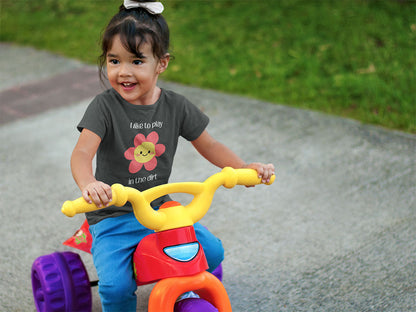Toddler riding a trike wearing an asphalt colored I like to play in the dirt tee