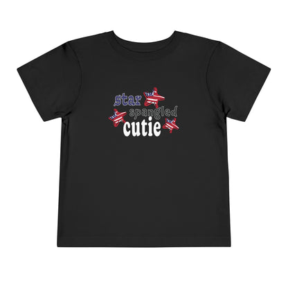 Black toddler t-shrit laying flat with typography and patriotic stars, t-shirt says "star spangled cutie"