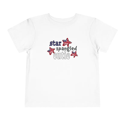 White toddler t-shrit laying flat with typography and patriotic stars, t-shirt says "star spangled cutie"