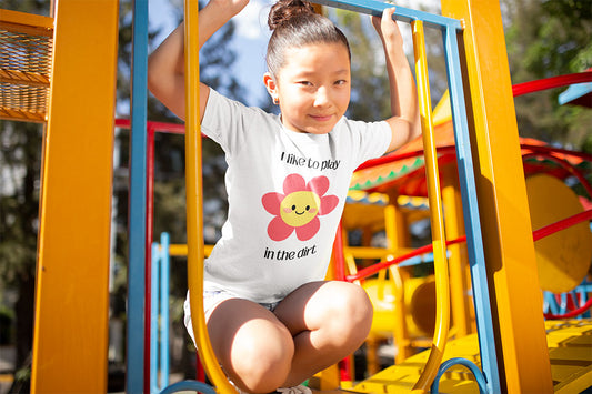 Kids’ dirt-loving t-shirt in playful outdoor setting- I love to play in the dirt with a pink flower