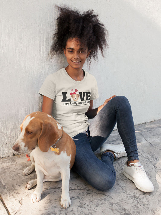 Dog parent wearing a “LOVE My Belly-Rub Addict” t-shirt with puppy peeking out in natural and sitting wilt her dog