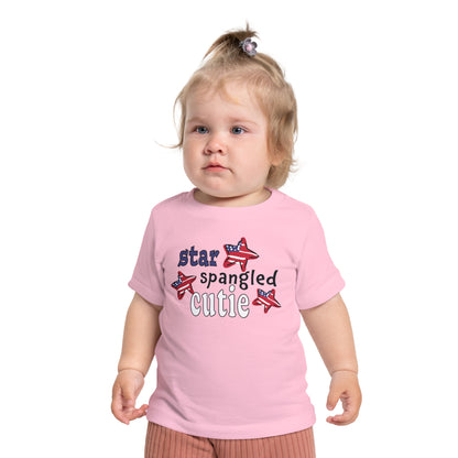 Baby wearing a pink t-shrit with typography and patriotic stars, t-shirt says "star spangled cutie"