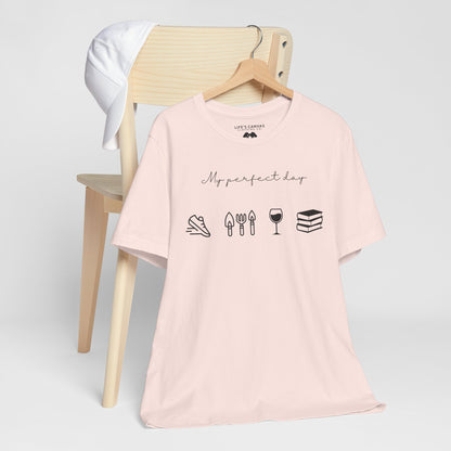 Unisex shirt with jog, garden, wine, and book icons on a hanger in soft pink