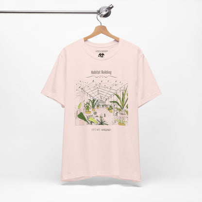 Unisex plant lover shirt that says “Habitat Building, It’s Not Hoarding” on a hanger in Soft Pink