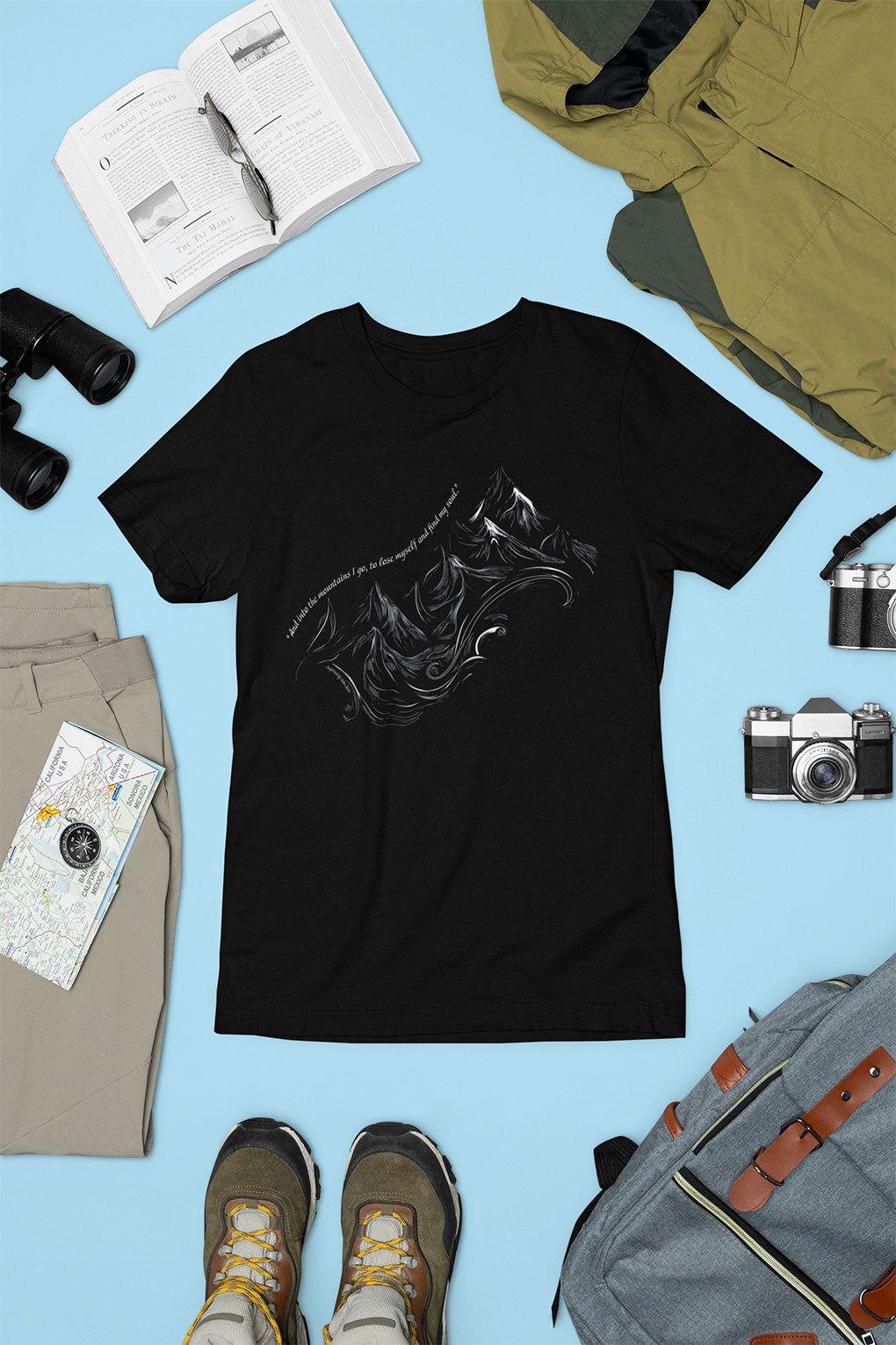 Flay Unisex t-shirt with sketched mountain design and John Muir quote “Into the Mountains I go...” surrounded by travel gear- Black