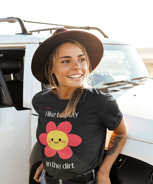 Woman leaning against truck adventuring while wearing I still like to play in the dirt dark grey t-shirt