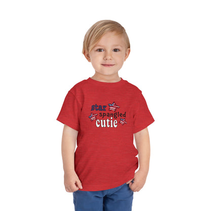 Red toddler t-shrit on a model with typography and patriotic stars, t-shirt says "star spangled cutie"