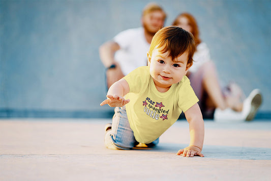 Baby crawling towards you wearing a light yellow t-shrit that says "star spangled cutie"